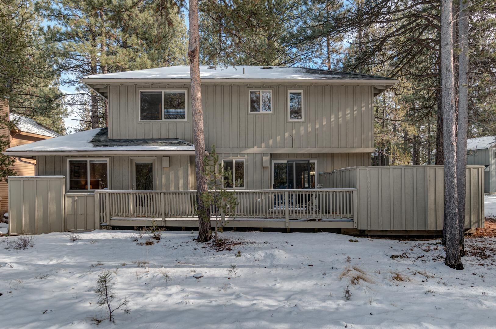 A two-story house with a front deck and a fenced yard.