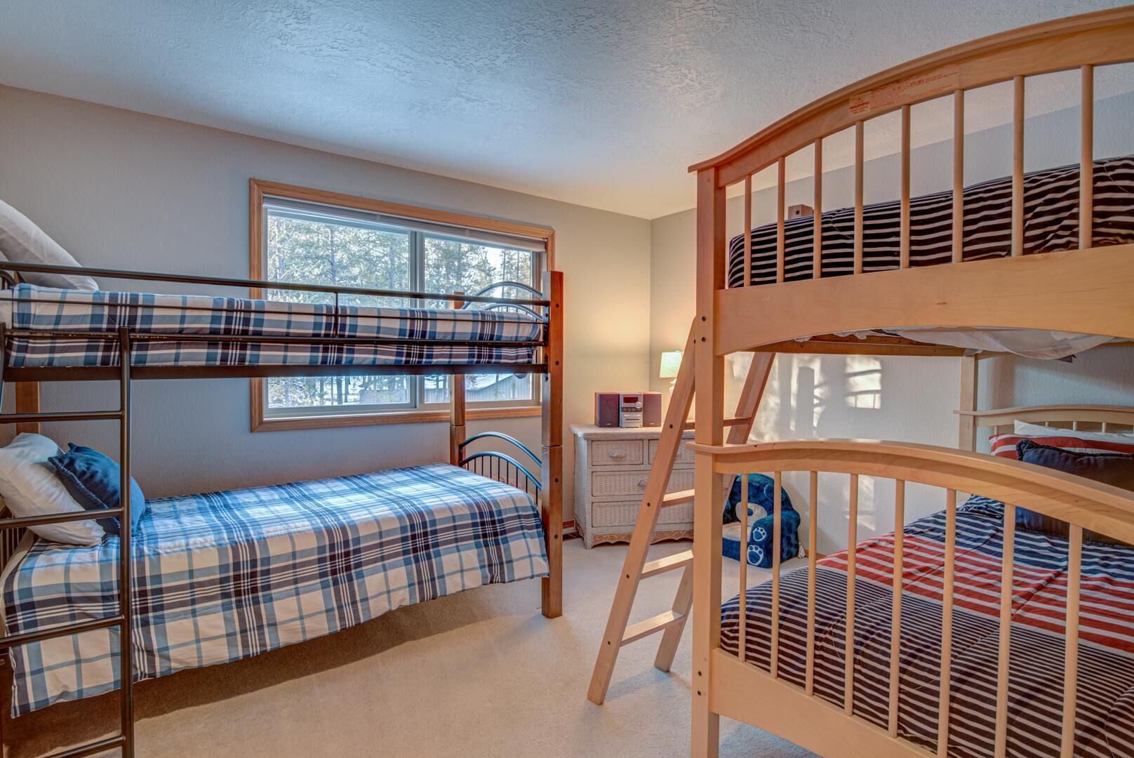 A bunk bed room with a window, a dresser, and a ladder.