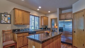 A modern kitchen with wooden cabinets, a central island, and a stainless steel refrigerator. - Jacinto Road 16831 (Bend)