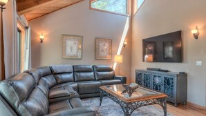 A living room with a leather sectional sofa, a glass coffee table, and a cabinet with a TV. - Loon Lane 13 (Bend)