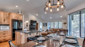 Une cuisine moderne avec des meubles en bois, un îlot central et un coin repas aménagé pour accueillir six personnes.