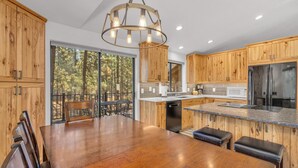 Une cuisine moderne avec des meubles en bois, un réfrigérateur en acier inoxydable et un coin repas comprenant une table et des chaises en bois.