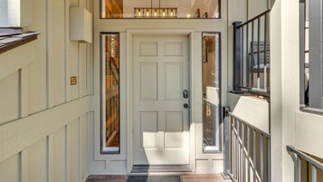 A white door with a keypad lock, a small window with a view of the interior, and a metal railing on the right side.