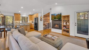 Un salon moderne avec un grand canapé, une table basse et une cheminée. Il y a également un coin cuisine avec des meubles en bois et une table à manger.