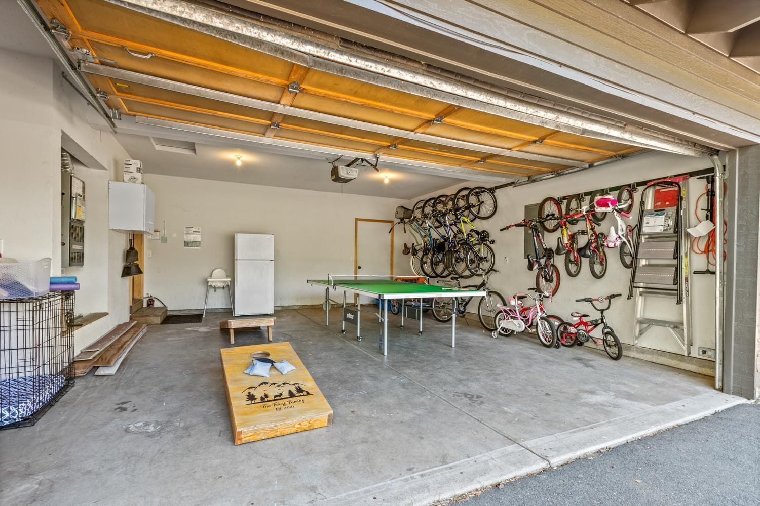 Ett garage med ett bordtennisbord, cyklar och ett litet bord med en bordsduk.
