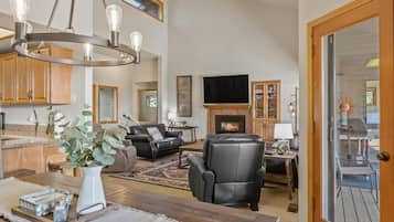 Amplia sala de estar con chimenea, muebles de cuero y un televisor grande.