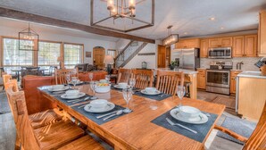 A spacious kitchen with wooden cabinets, stainless steel appliances, and a dining area with a large wooden table set for six. - Lassen Lane 3 (Bend)