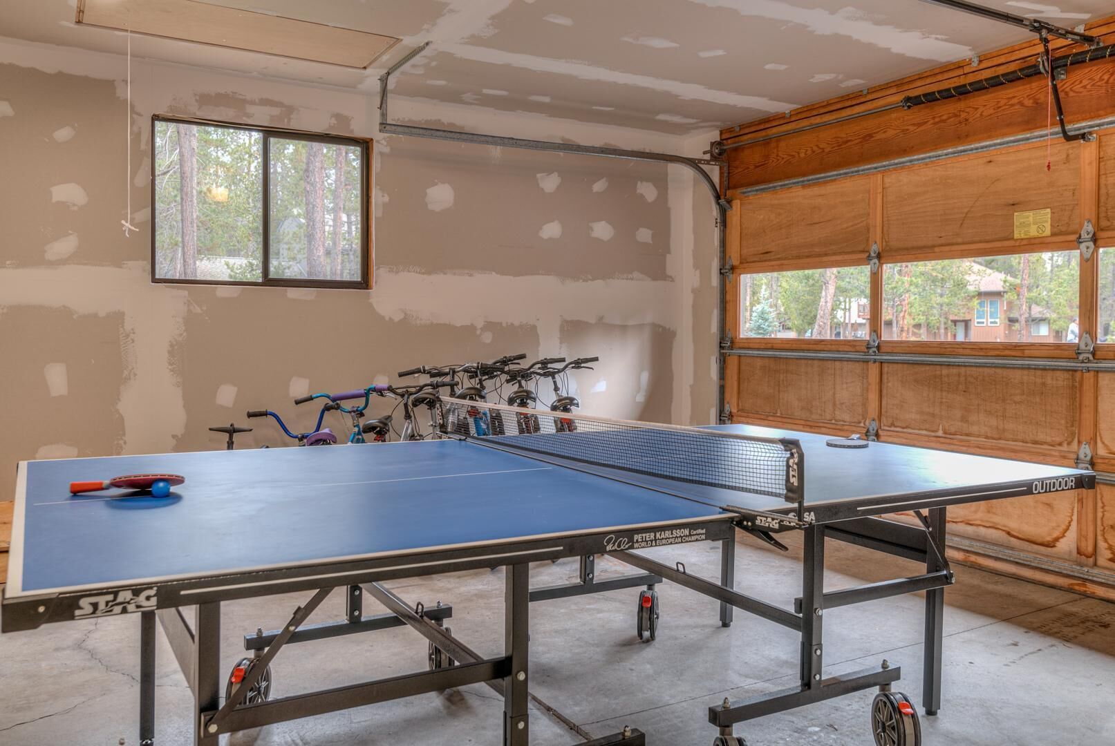 A ping pong table in a room with unfinished walls and a window.
