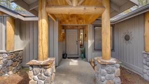 A wooden porch with stone pillars, a stone wall, and a door leading to a house. - Kinglet Lane 46 (Bend)