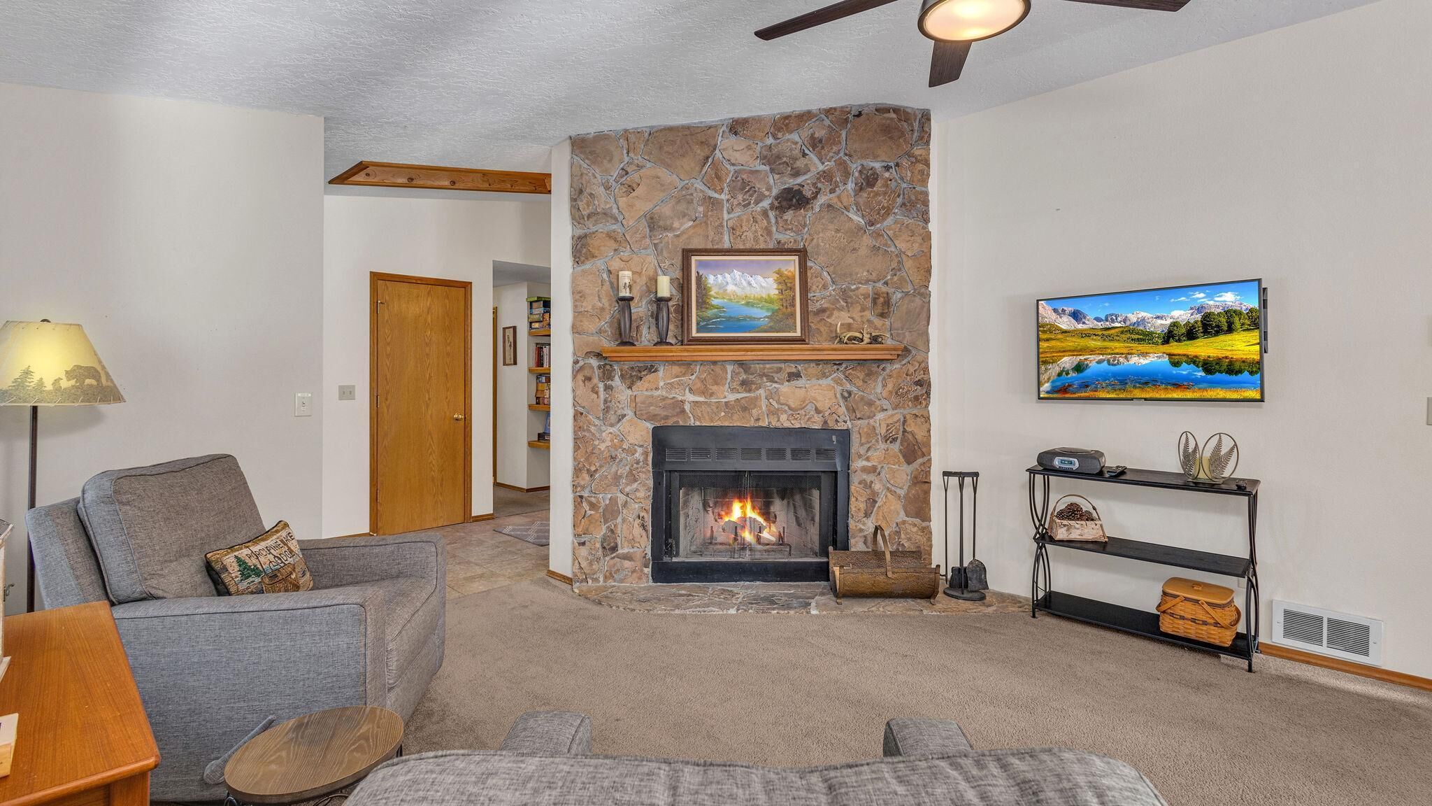 A living room with a stone fireplace, a television, and a cozy seating area.