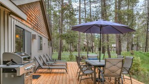 An outdoor deck with a grill, lounge chairs, and a table with an umbrella. - Kinglet Lane 46 (Bend)
