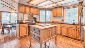 A spacious kitchen with wooden cabinets, a central island, and large windows providing natural light.