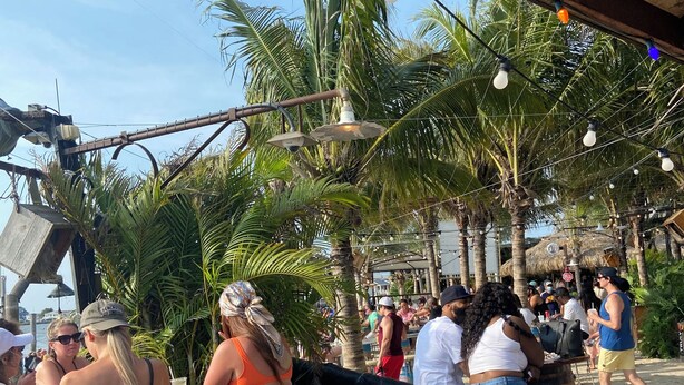 A beachside bar with outdoor seating, palm trees, and a wooden ceiling structure. - Spacious home with private pool & game room. Sleeps 15. Close to Ocean City.  (Salisbury)