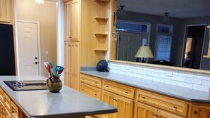 A kitchen with wooden cabinets, a black countertop, and a built-in stove. There is a stool and a vase with utensils. - 5 bdr vacay everyone will LOVE (Loudon)