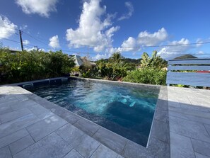 A swimming pool with clear water, surrounded by stone tiles and lush greenery. - Comfort & privacy - 2 master suites (Sainte-Anne)
