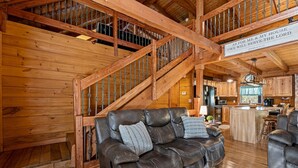 A wooden interior with a leather sofa, a staircase, and a kitchen area.
