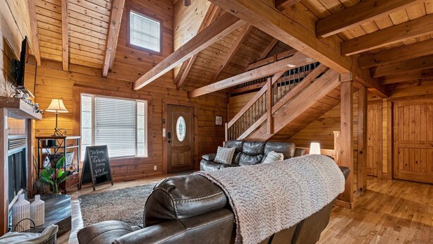 A wooden interior with a leather sofa, a staircase, and a fireplace.