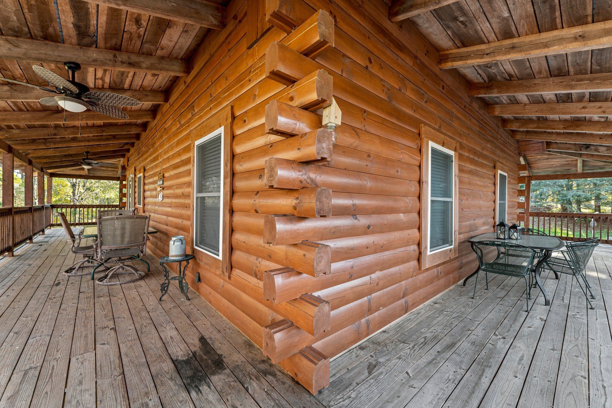 A wooden cabin with a porch, two windows, and a ceiling fan.