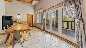 A spacious kitchen with a large wooden table, modern chairs, and a built-in oven.