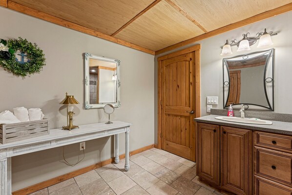 Un baño con tocador de madera, un espejo y un lavabo.