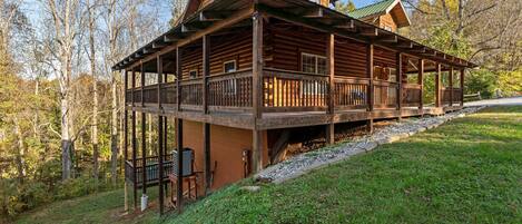 A log cabin with a covered porch and a fireplace.