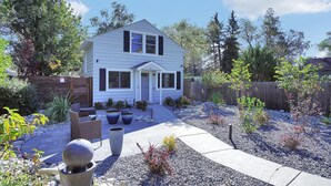 A two-story house with a front porch, a driveway, and a garden with various plants and a patio area. - Cheerful Lake House minutes from all Colorado Springs has to offer! (Colorado Springs)
