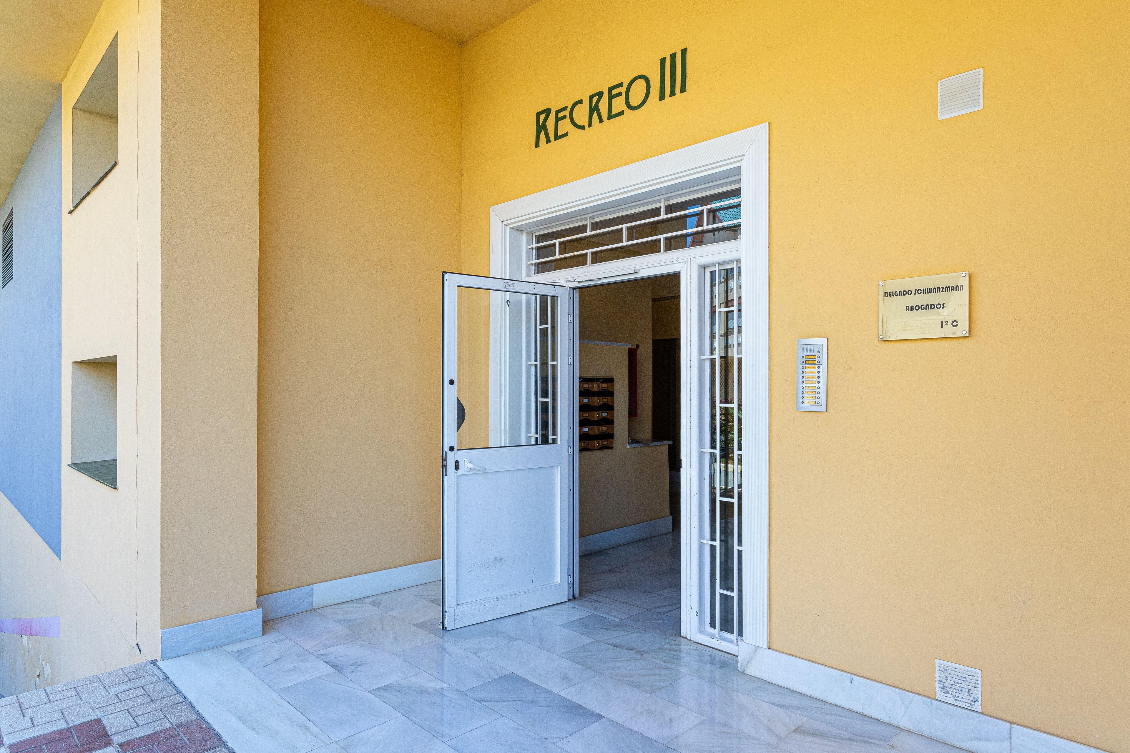 A building entrance with a sign reading "RECREO III" and a temperature control sign.
