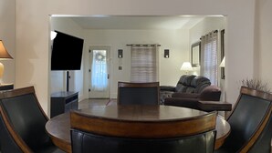 A dining area with a round table and chairs, a sofa, a television, and a lamp. - 5 ★ 5min → Downtown/Shopping ★ Smart TVs ★ Balcony (Grand Rapids)