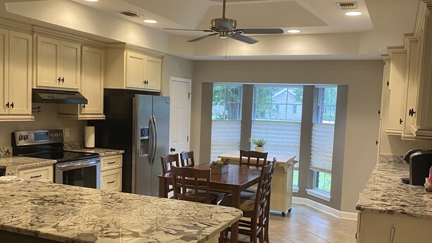 A spacious kitchen with a large island, dark wooden chairs, and a dining table. - Brick home in a quiet quaint neighborhood. Just minutes off the beach express. (Foley)