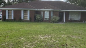 A two-story brick house with a front porch, a lawn, and a large tree. - Brick home in a quiet quaint neighborhood. Just minutes off the beach express. (Foley)