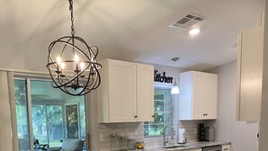 A modern kitchen with white cabinets, a glass dining table, and a chandelier. - 🌴Tropical Retreat in Sarasota  (Sarasota)