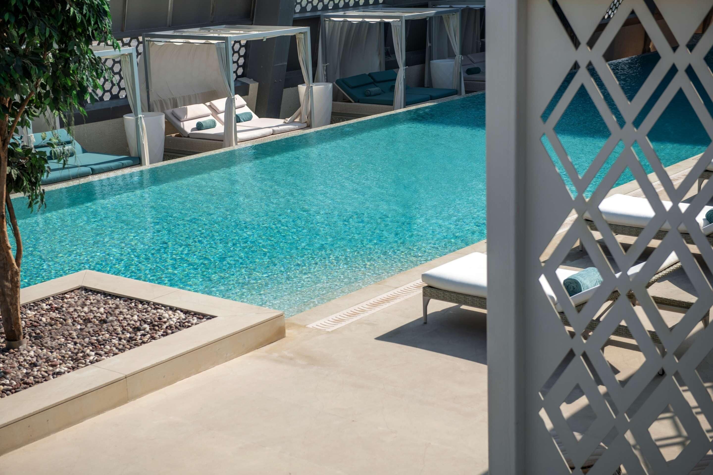 Un área de piscina con sillones de descanso y una estructura tipo toldo.
