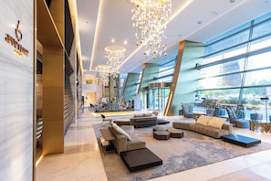 Un vestíbulo amplio con muebles modernos, ventanas grandes e iluminación decorativa.