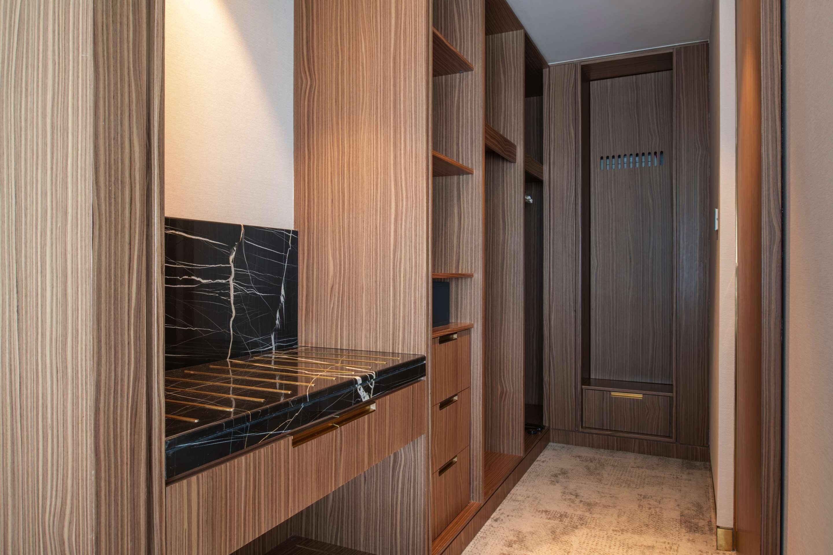 A walk-in closet with wooden shelving and a marble countertop.