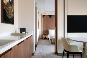 Una habitación de hotel moderna con área de cocina, una mesa de comedor y una cama.