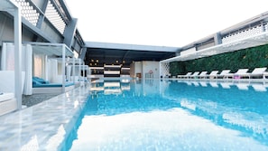 Una piscina interior moderna con sillas de descanso y un área de estar cubierta.
