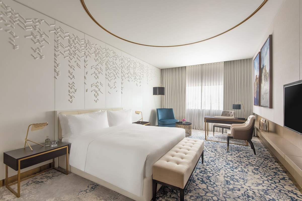 Habitación de hotel moderna con una cama grande, un escritorio, una silla y un televisor.
