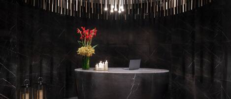 A reception desk with a laptop, candles, and flowers.