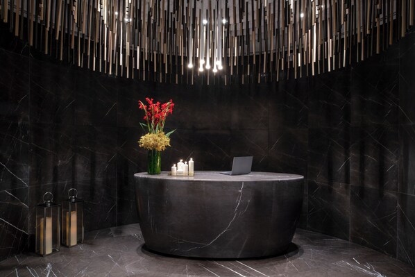 A reception desk with a laptop, candles, and flowers. - Steigenberger Hotel Doha (Doha)