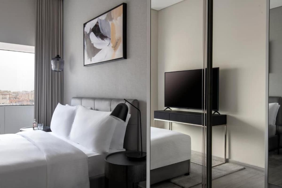 Una habitación de hotel moderna con una cama grande, un televisor de pantalla plana y vistas a la ciudad.