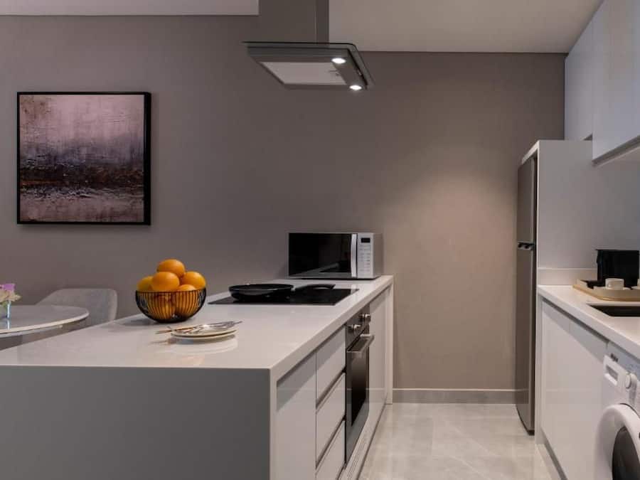 A modern kitchen with a central island, a microwave, a stove, and a washing machine.