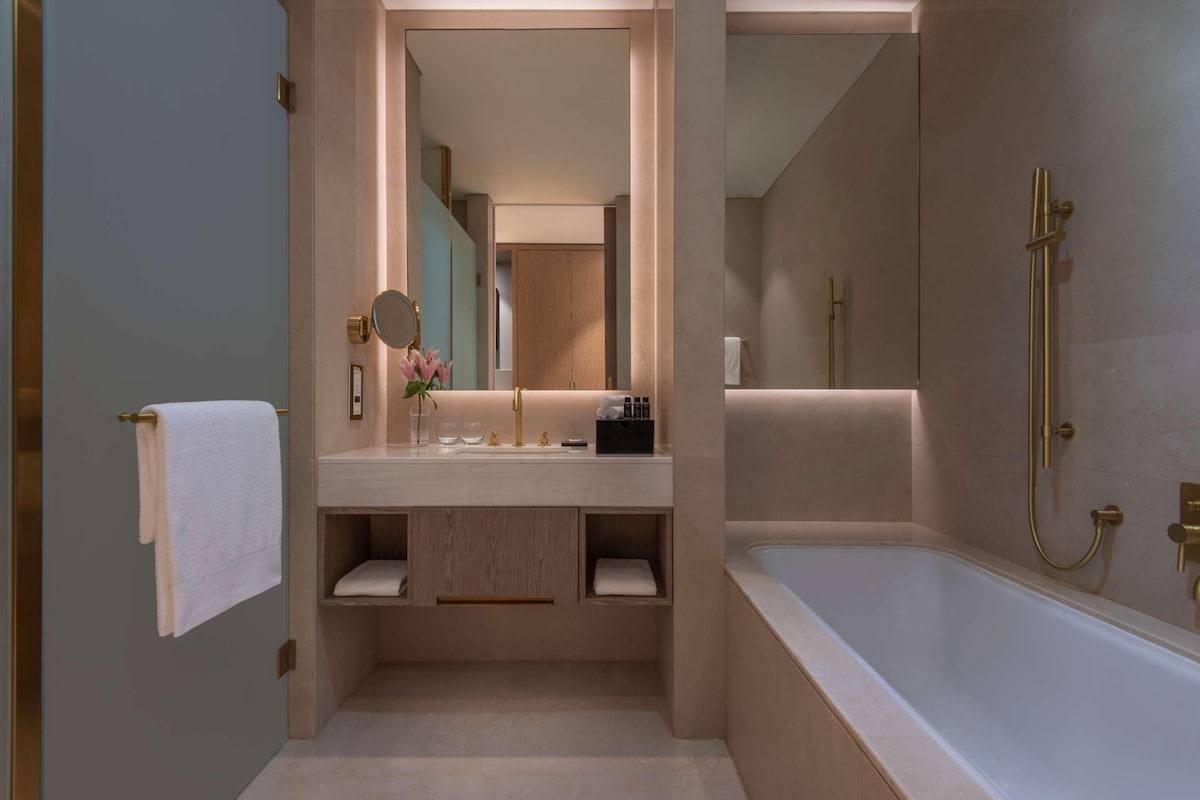 Un baño moderno con una bañera grande, un tocador con espejo y un perchero para toallas.