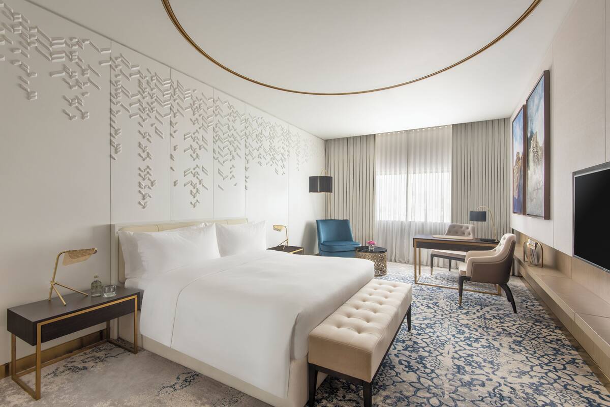 Habitación de hotel moderna con una cama grande, un escritorio, una silla y un televisor.
