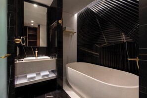 Un baño moderno con una bañera independiente, un tocador con espejo y un perchero para toallas.