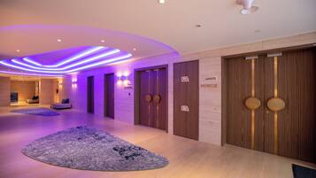 A modern hotel lobby with a wooden reception desk, a reception area, and a hallway leading to rooms.