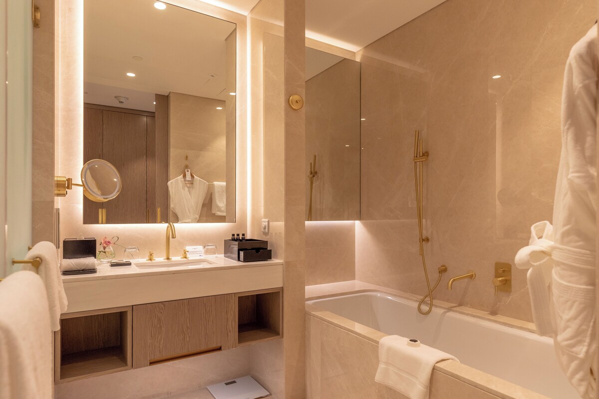 Ein modernes Badezimmer mit einem großen Spiegel, einer Badewanne und einem Waschtisch mit Spüle und Handtuchhalter.