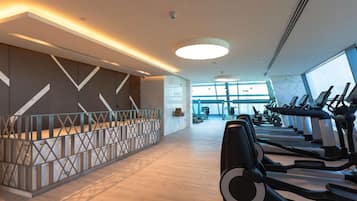 A modern gym with treadmills, a marble wall, and a glass partition.