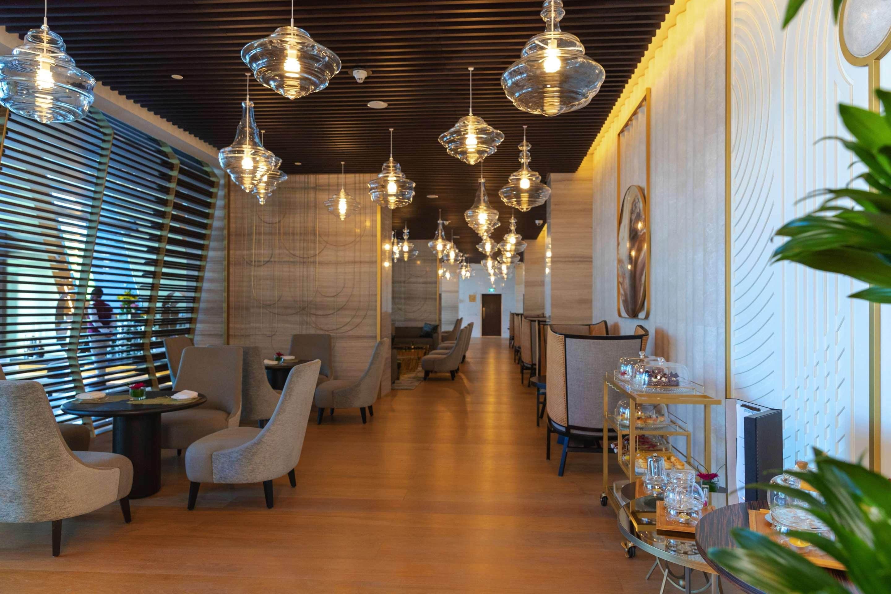 A modern interior with multiple seating areas, pendant lighting, and a central aisle.