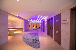 Un moderno vestíbulo de hotel con una recepción, una zona de estar y un cartel que indica Múnich.