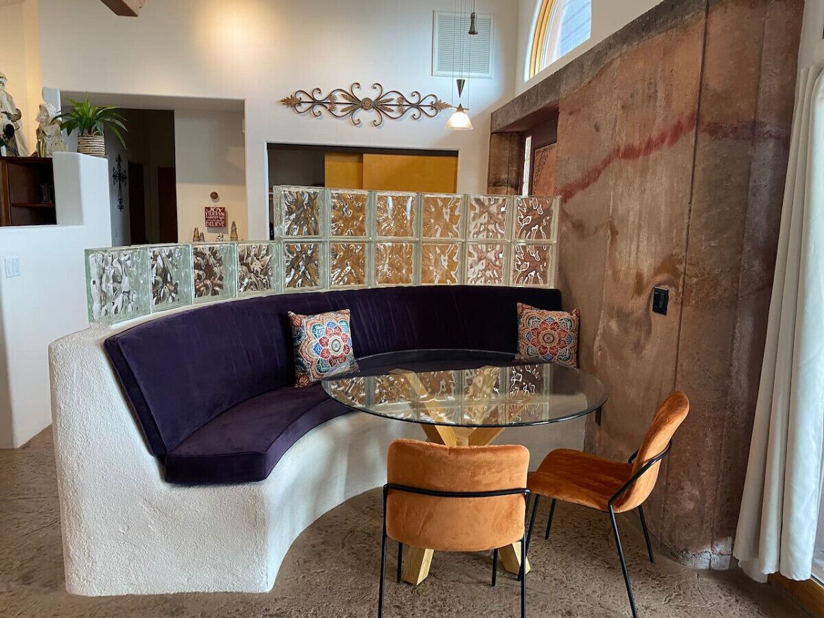 Uma sala de estar moderna com um sofá curvo, uma mesa de centro de vidro e duas cadeiras.
